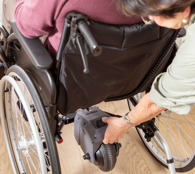 helping elderly wheelchair user in park